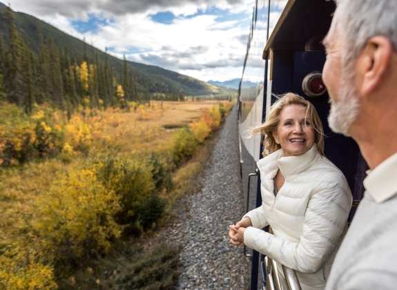 happy couple on platform of Rocky Mountaineer during train holiday