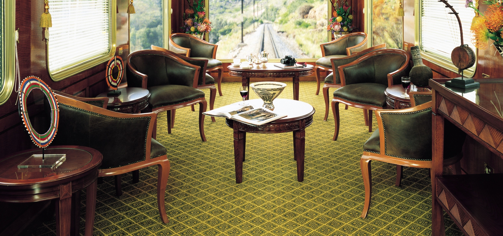 Inside a luxurious train carriage, lounge chairs and coffee tables