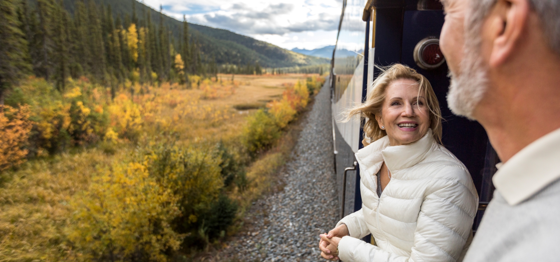 happy couple on platform of Rocky Mountaineer during train holiday