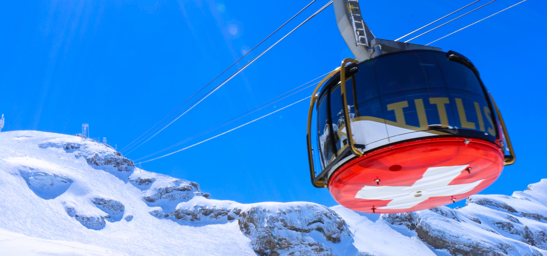 A cable car travels high over snowy peak