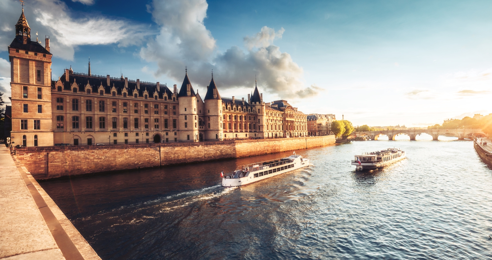 Dramatic sunset over river Seine and Conciergerie in Paris, France, with cruise boats and Pont Neuf. Colourful travel background. Romantic cityscape.