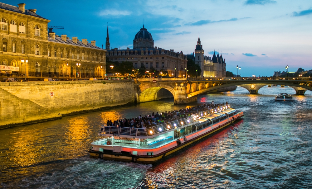 Bateau Mouche cruising on Seine river at sunset, Paris.