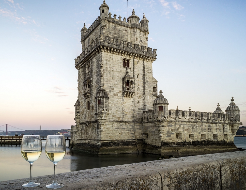 The Tower of Belem in Lisbon, Portugal with two glasses of white wine in the foreground.