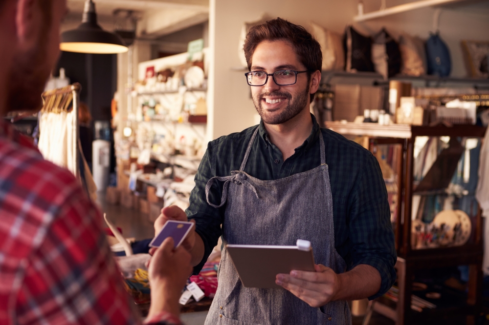 Sales Assistant With Credit Card Reader On Digital Tablet