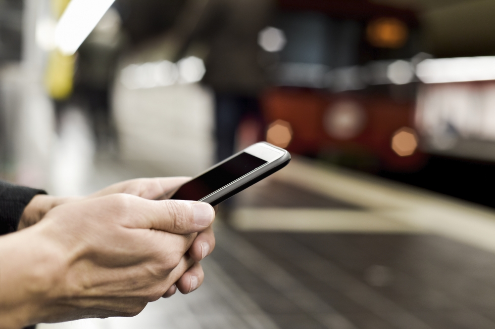 man using smartphone in underground station