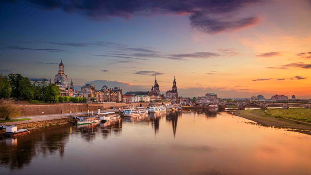 Panoramic cityscape image of Dresden, Germany with reflection of the city in the Elbe river, during sunset.
