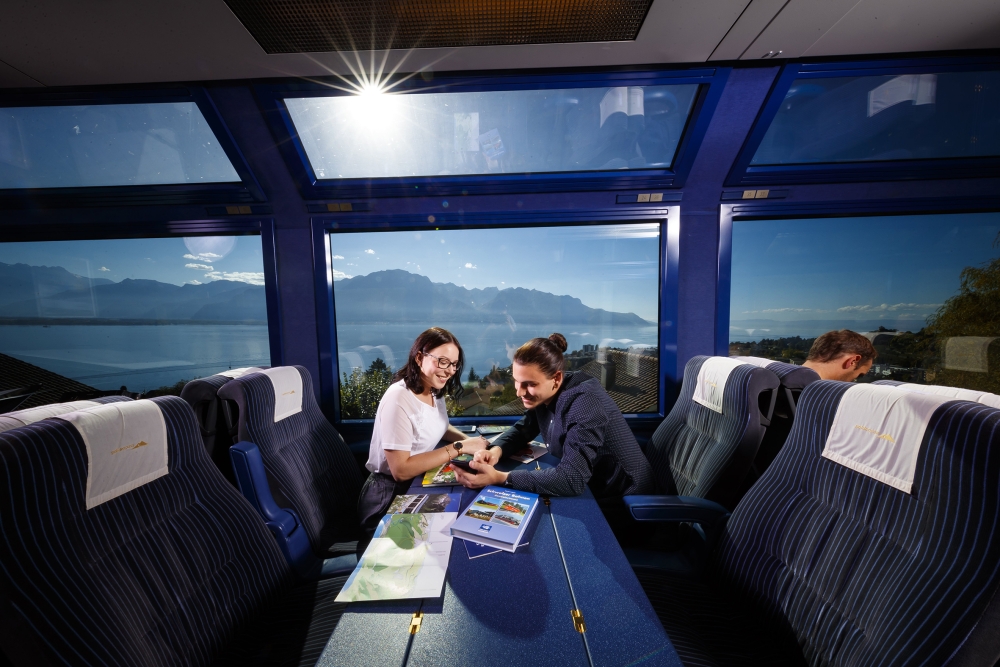 Panoramic carriages of the GoldenPass A couple on a train looking at a map