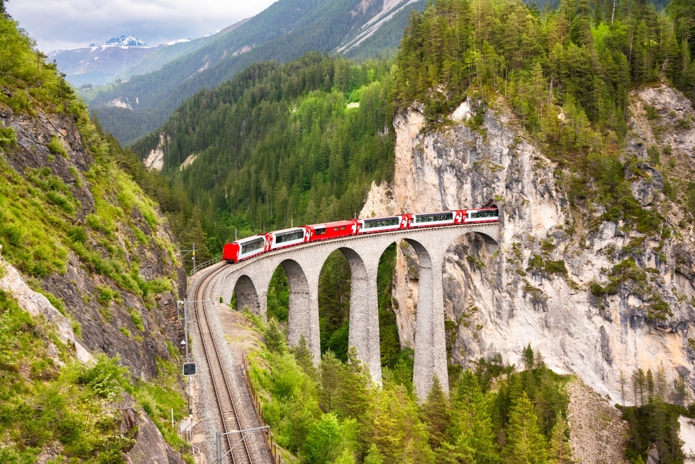 Swiss red train on viaduct in mountain, scenic ride