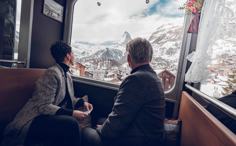 a couple sitting in nostalchic class onboard the gornergrat looking out the window in winter